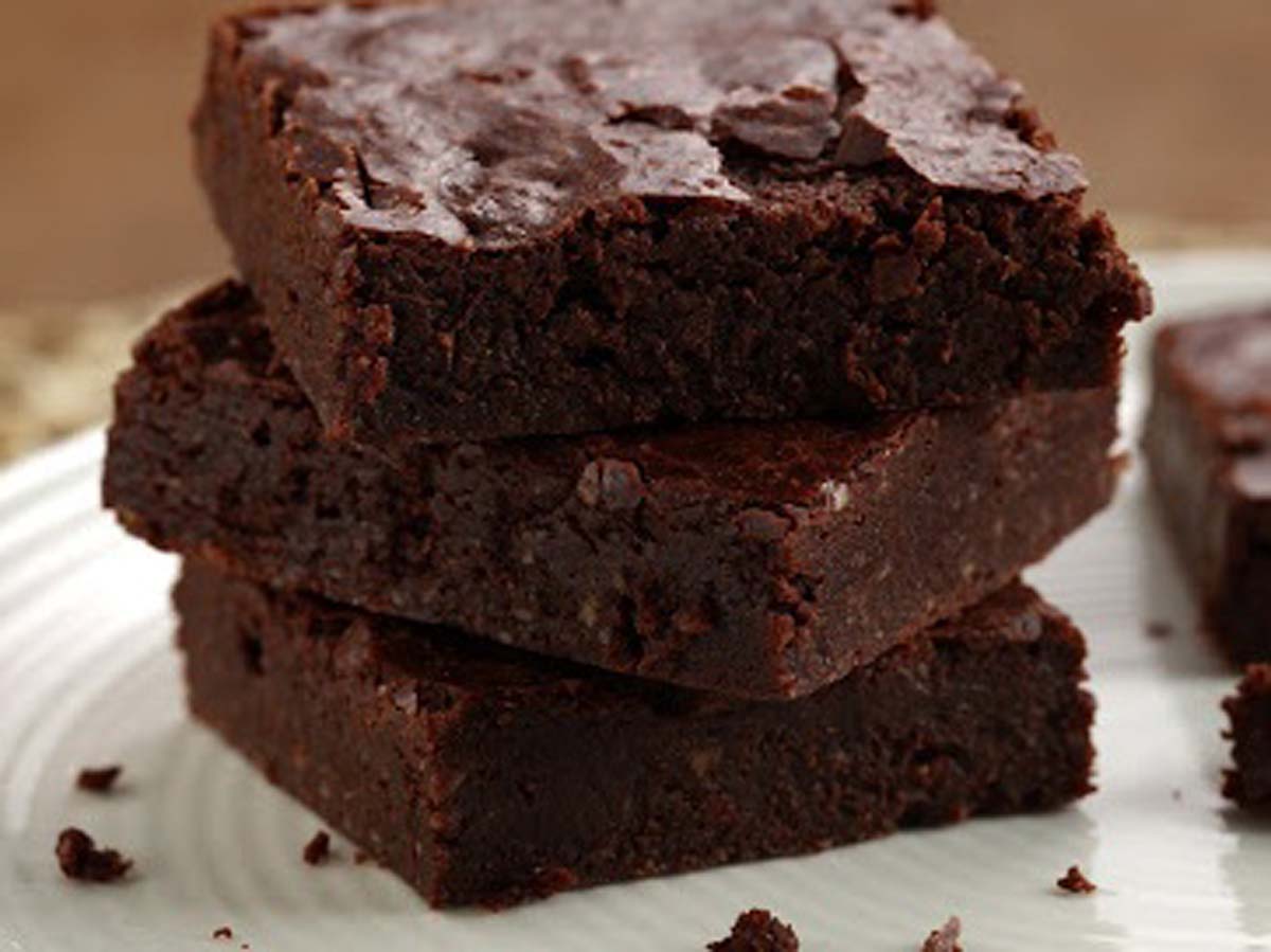 Fudgy and dense chocolate brownies sliced into thick squares on a wire rack.