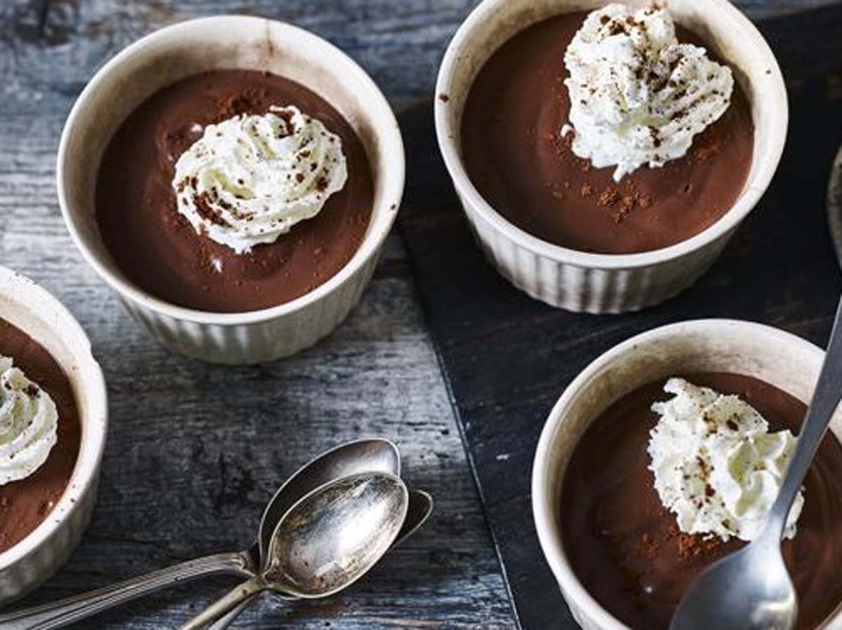 Individual rich chocolate pots de creme desserts chilled in ceramic ramekins.