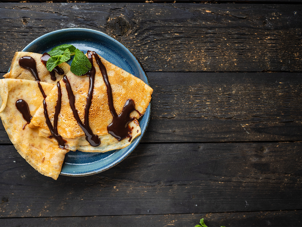 A decadent rich dark chocolate sauce pouring smoothly onto a dessert bowl.
