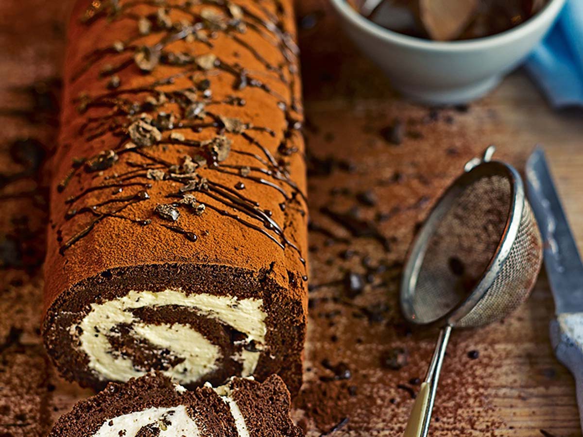 A beautiful chocolate swiss roll cake swirled cleanly with white cream filling.