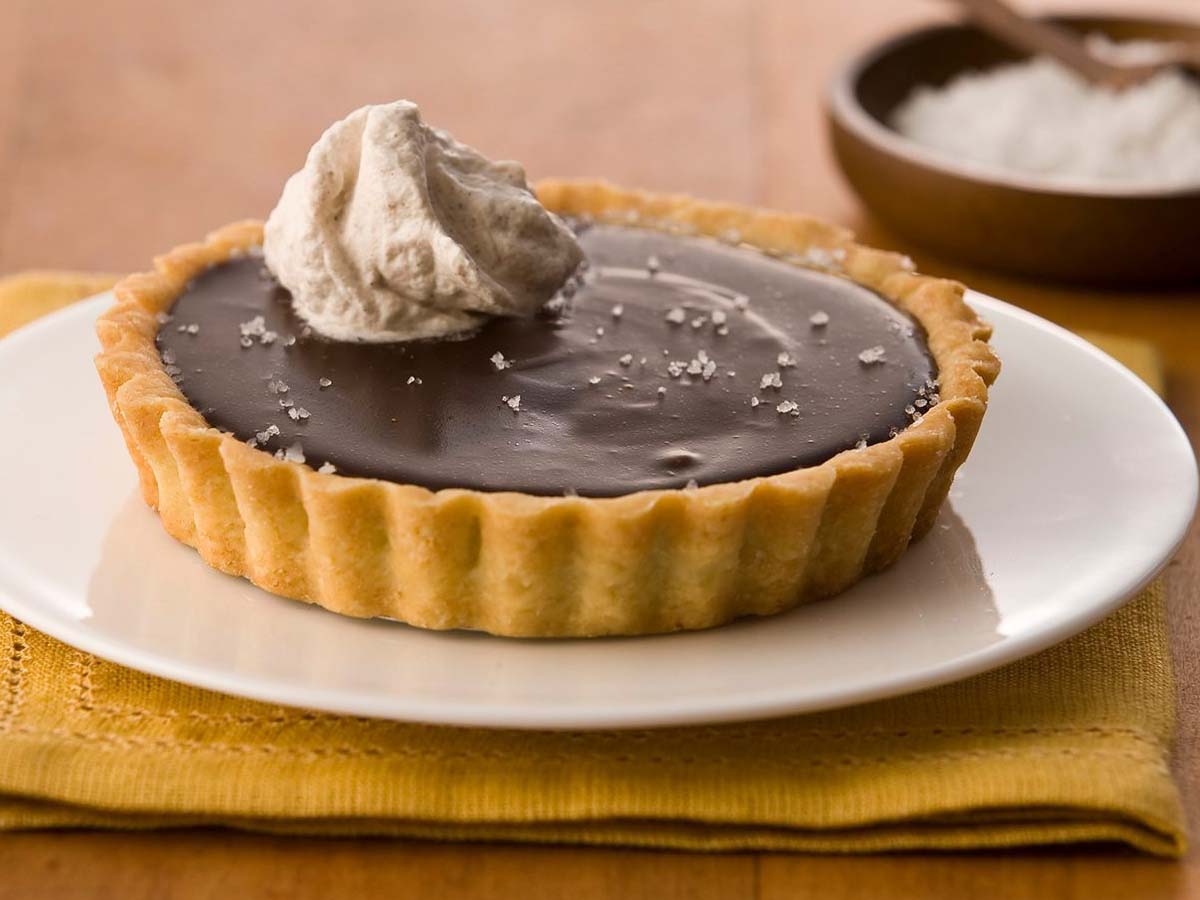 A sleek and glossy dark chocolate tart in a crisp pastry shell.