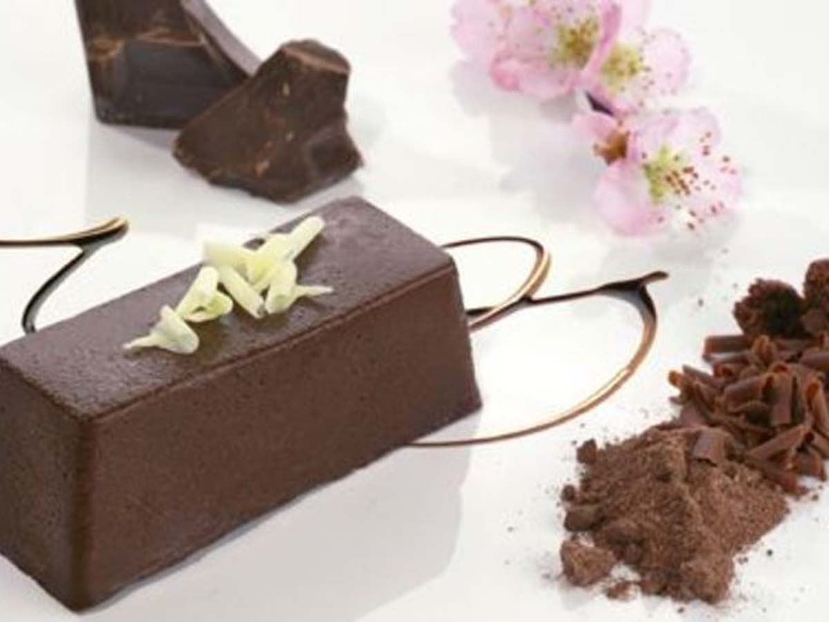 A dense and rich chocolate terrine dessert sliced on a modern serving board.
