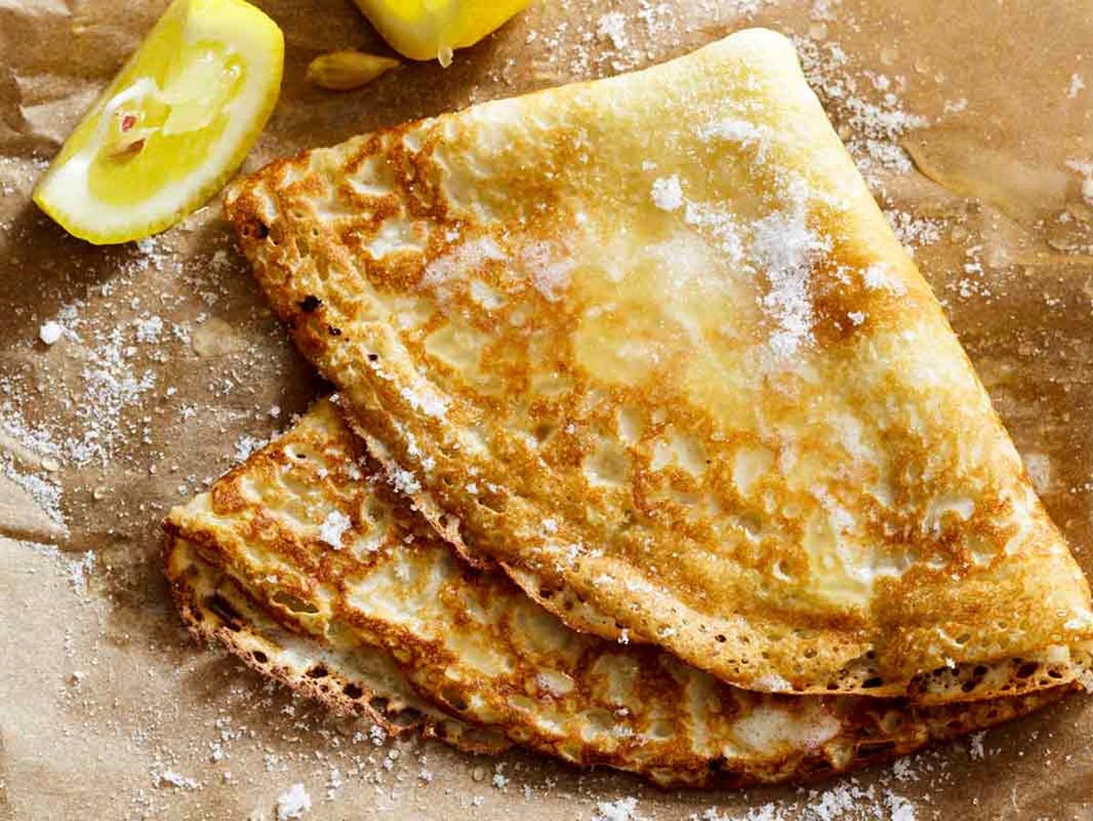 A tall stack of thin, golden brown French crepe pancakes ready for sweet toppings.
