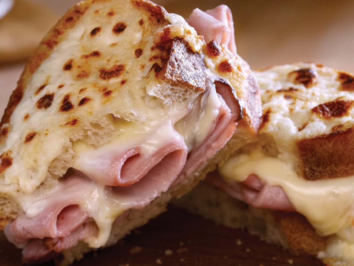 A gourmet grilled Croque Monsieur sandwich with melted gruyere cheese and ham.