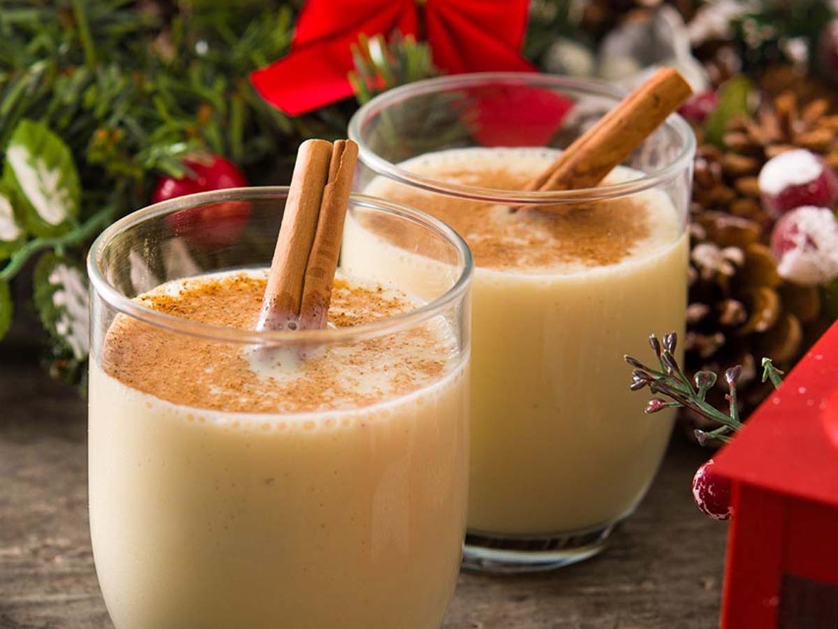 A festive glass cup filled with thick, creamy holiday eggnog sprinkled with nutmeg powder.