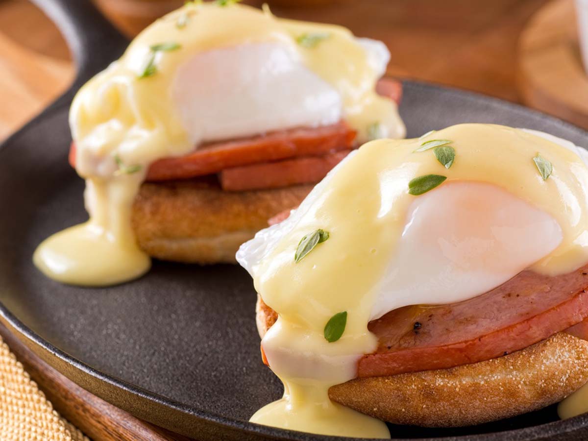 Classic eggs benedict with poached eggs and ham over toasted English muffins.