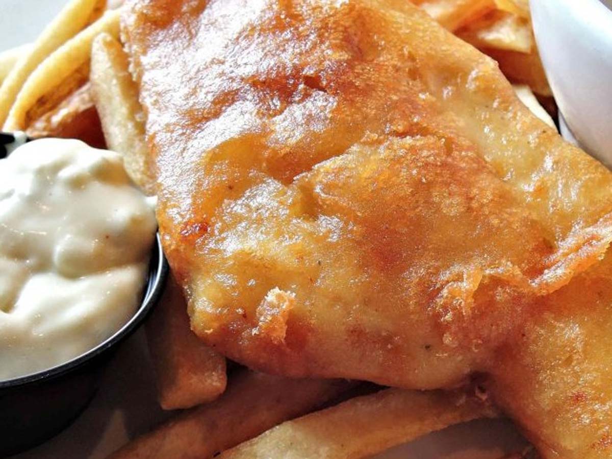 A classic newspaper basket of crispy beer-battered fish and golden potato chips.