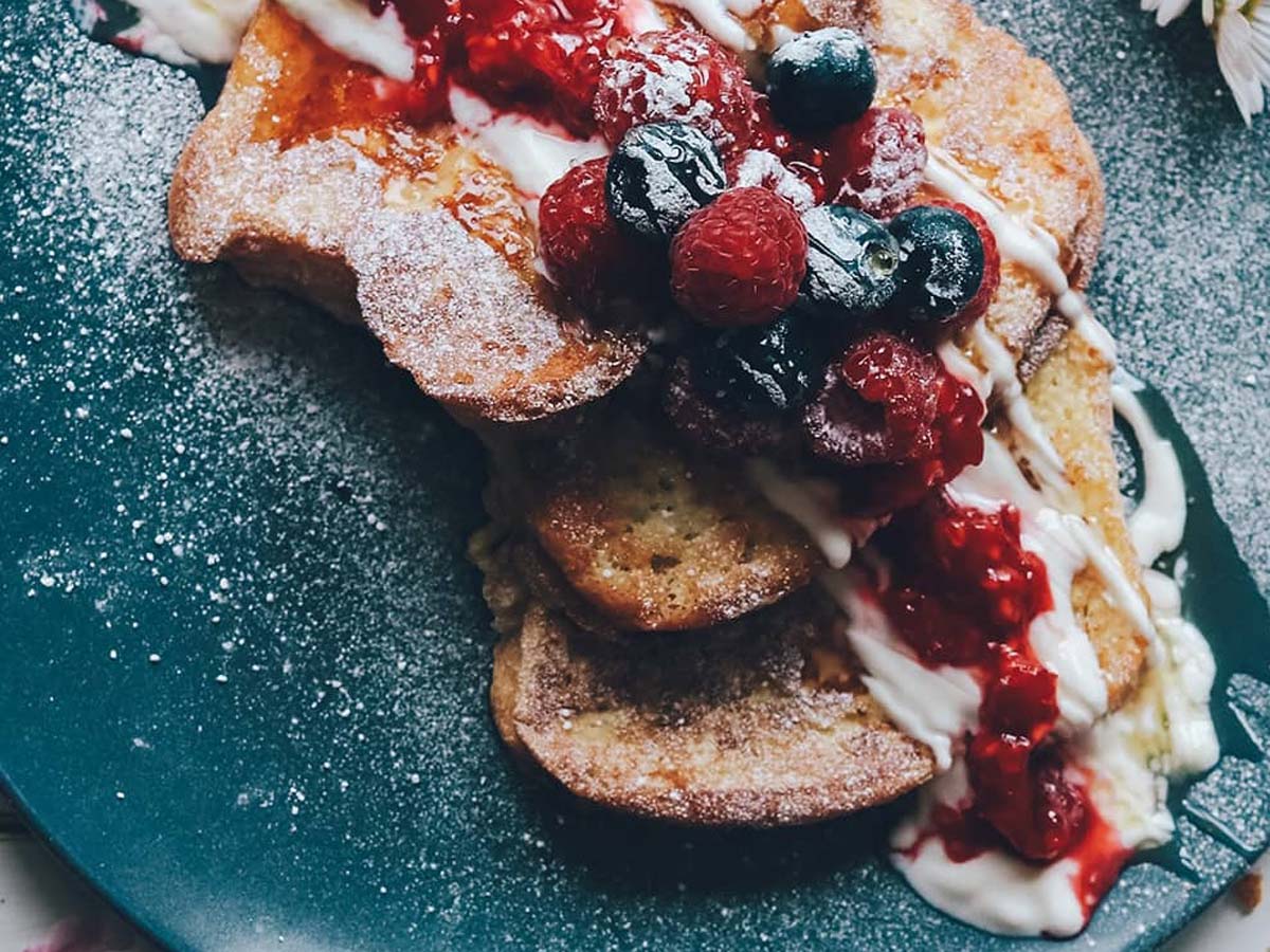 Healthy French toast topped with thick creamy yogurt, mixed wild berries, and honey drizzle.