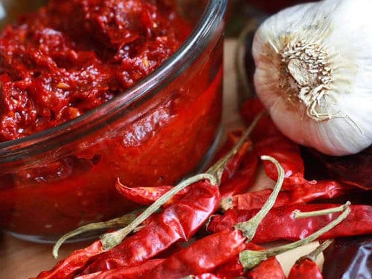 A deep red, fiery North African harissa paste chili sauce mix inside a jar.