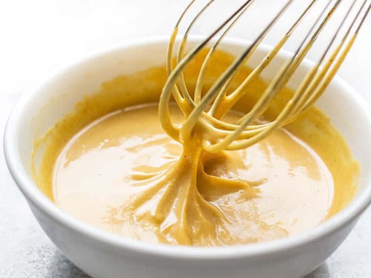 A smooth, creamy yellow honey curry mayonnaise dip sauce inside a ramekin bowl.