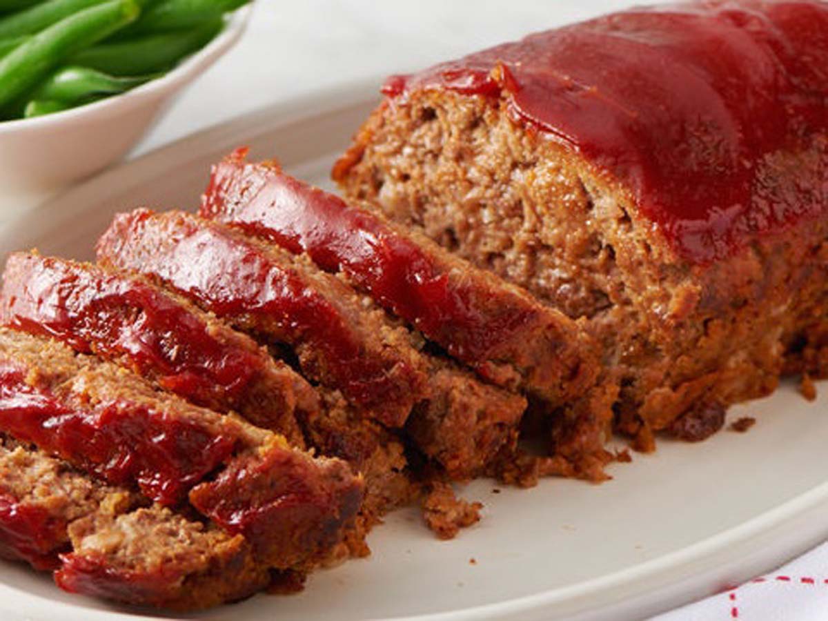 A hearty, dense homemade savoury baked meatloaf sliced clean on a serving platter.