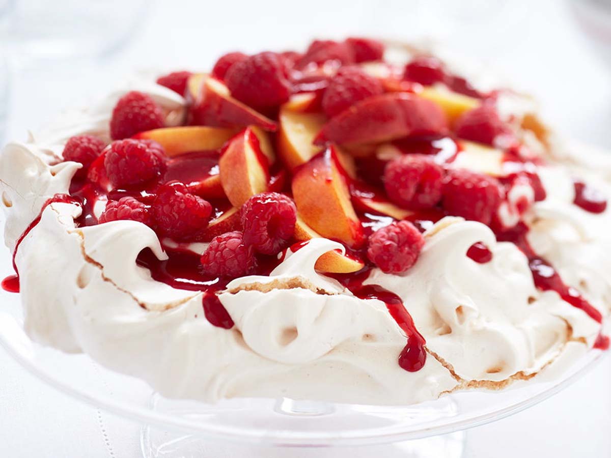 A light and airy crisp pavlova meringue shell topped with whipped cream and fresh fruits.