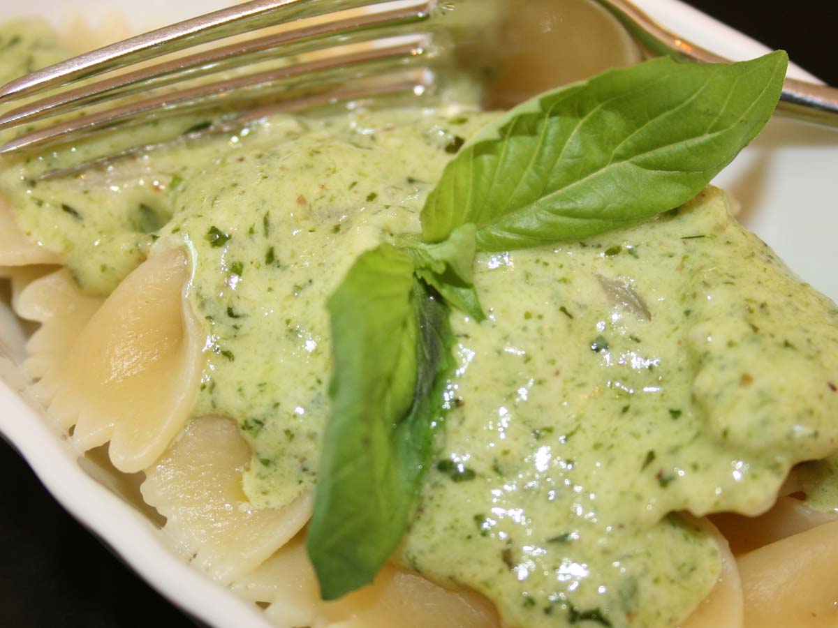 A creamy green pesto pasta sauce blending fresh basil, garlic, and cream.
