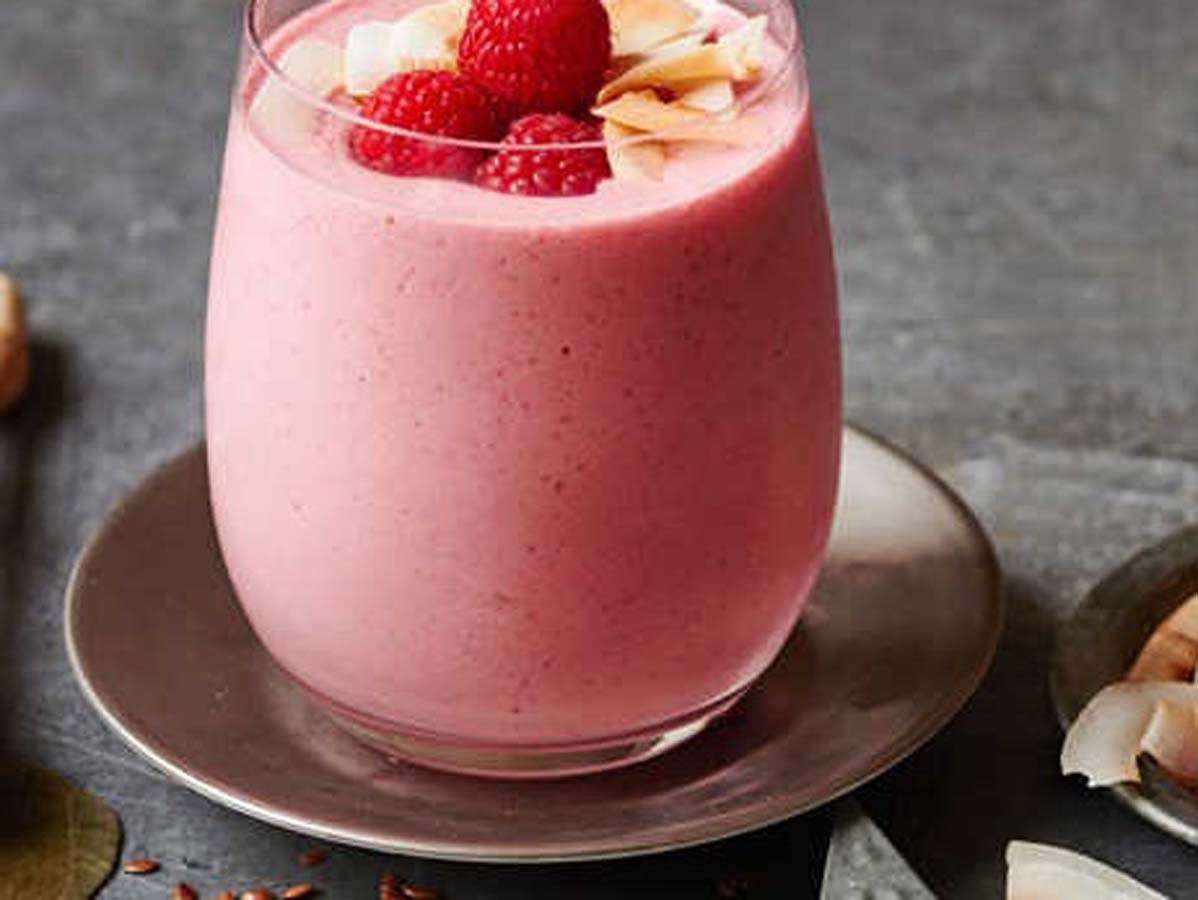 A vibrant, bright pink blended wild raspberry smoothie garnished with fresh raspberries.