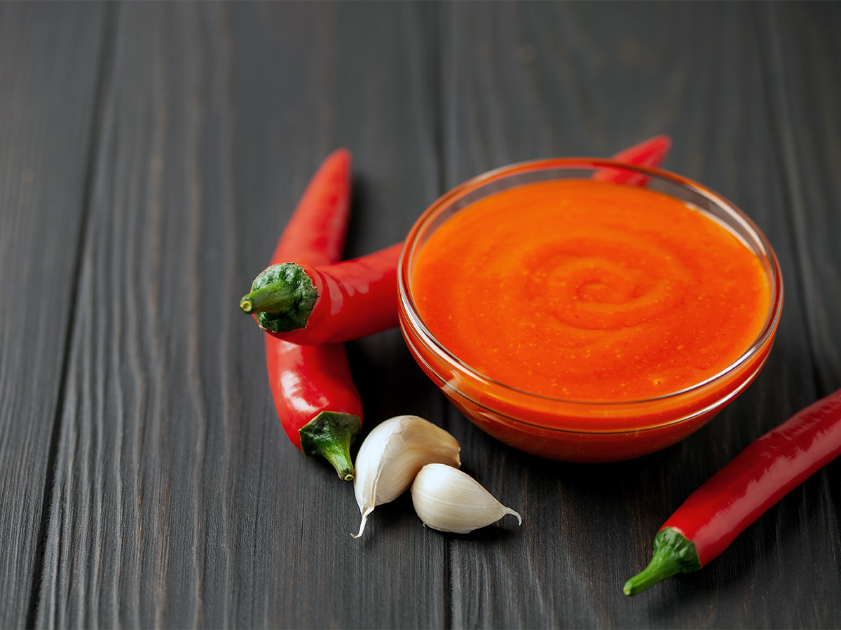 A smooth and vibrant red blended roasted red pepper sauce inside a serving bowl.