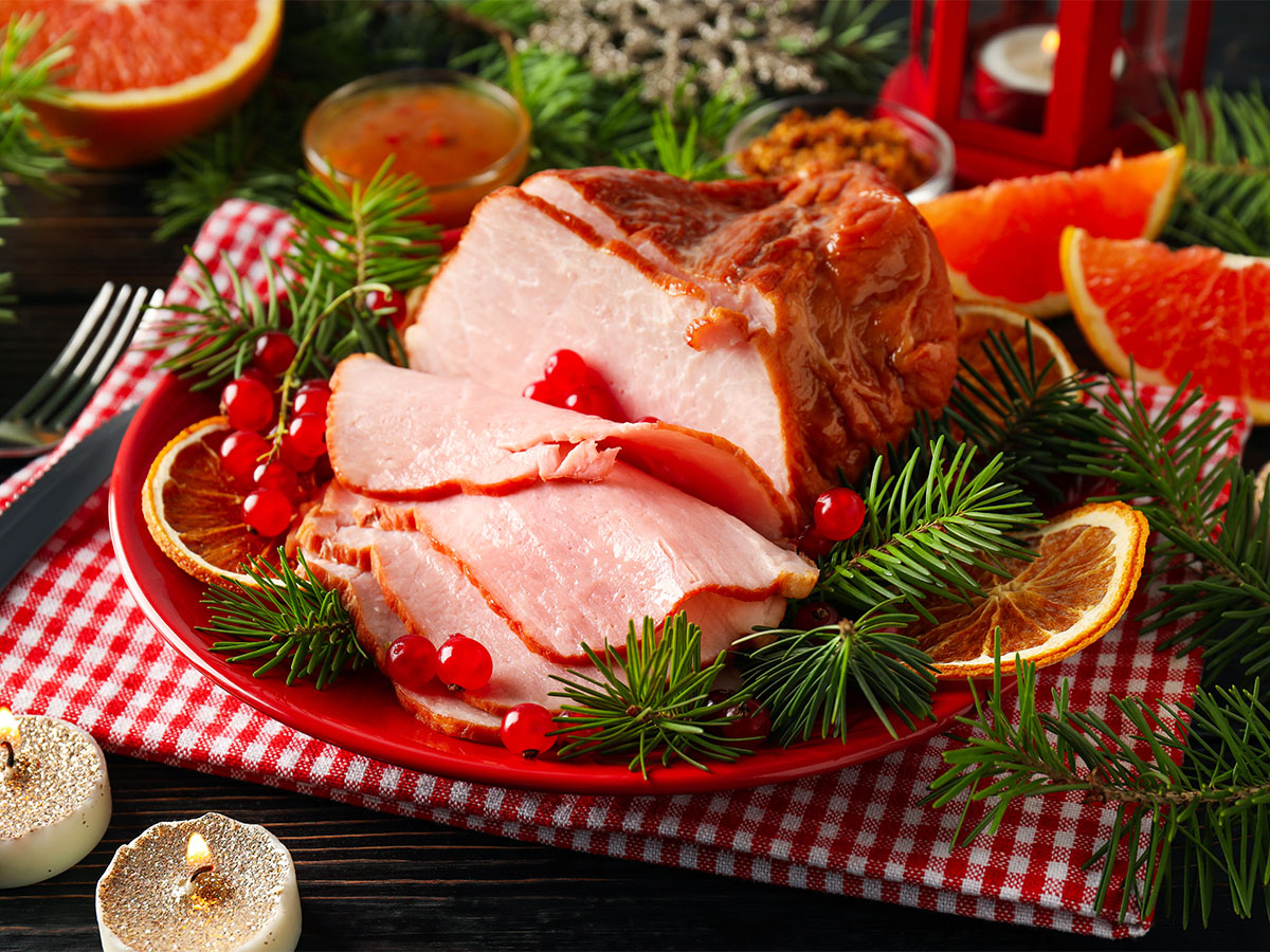 A premium wood-smoked Christmas ham holiday centerpiece roast on a carving board.