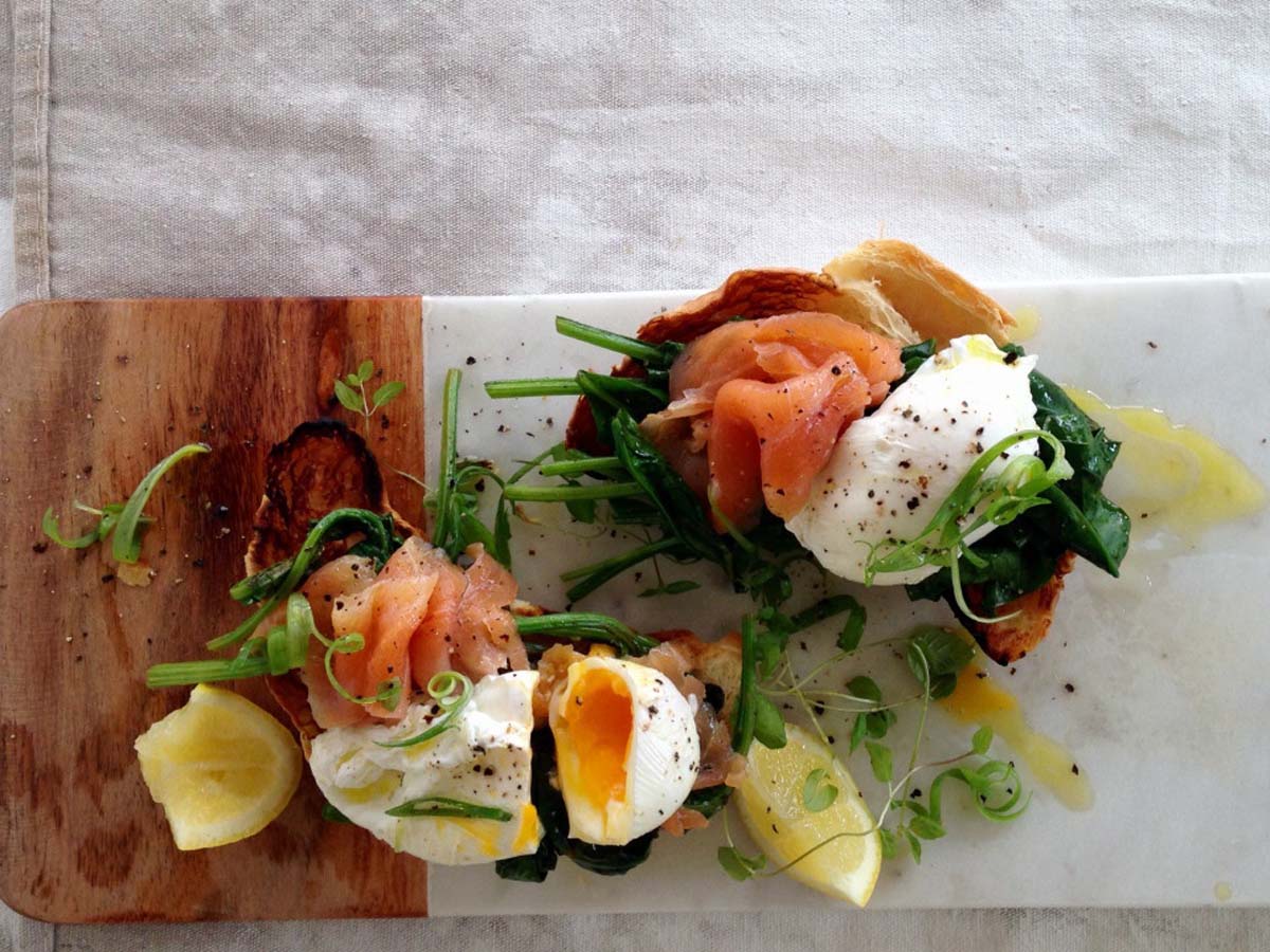 A luxury breakfast croissant stuffed with smoked salmon ribbons, cream cheese, and a poached egg.