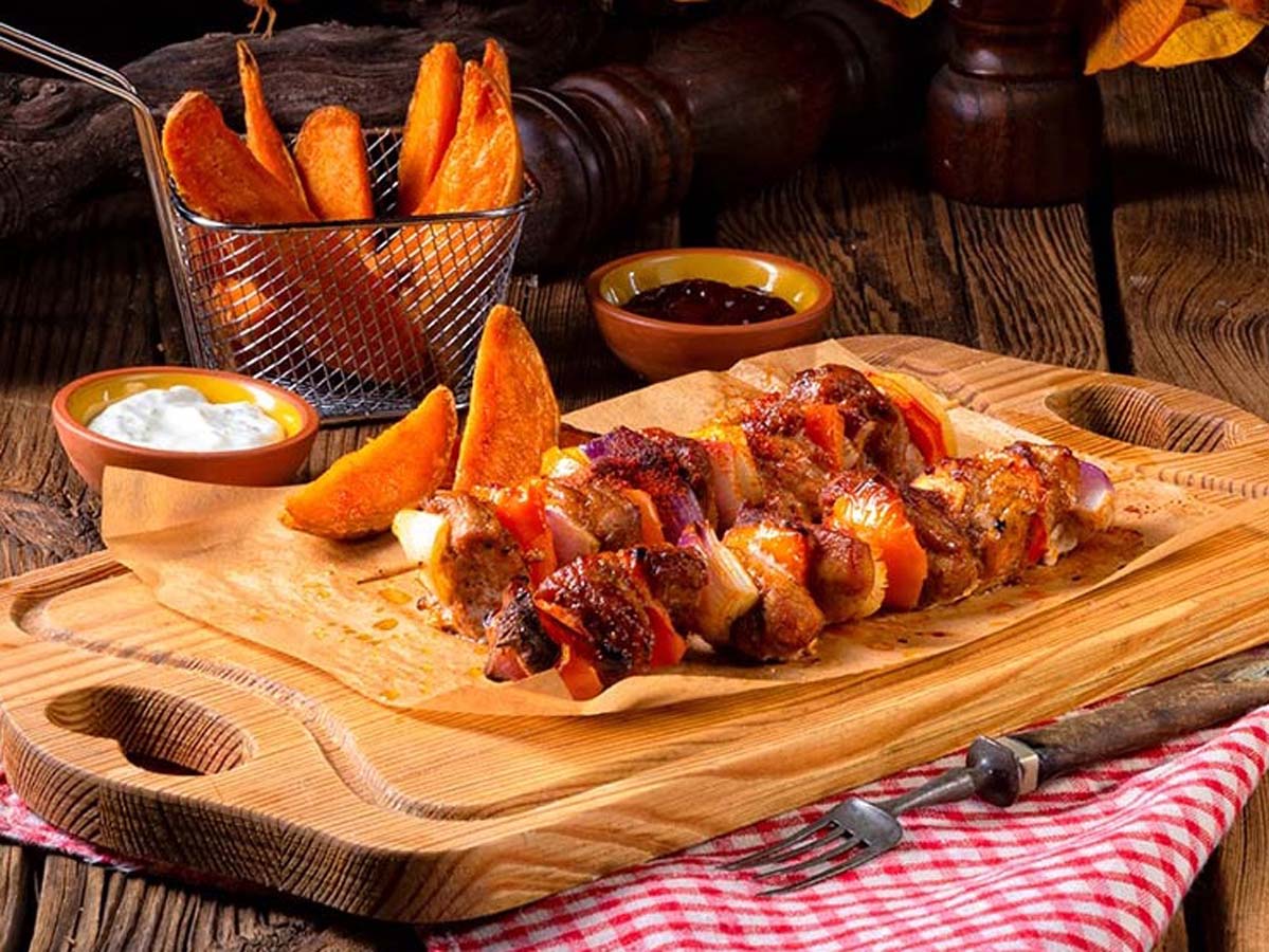 Traditional South African spiced lamb kebabs sosaties grilled over hot braai barbecue coals.