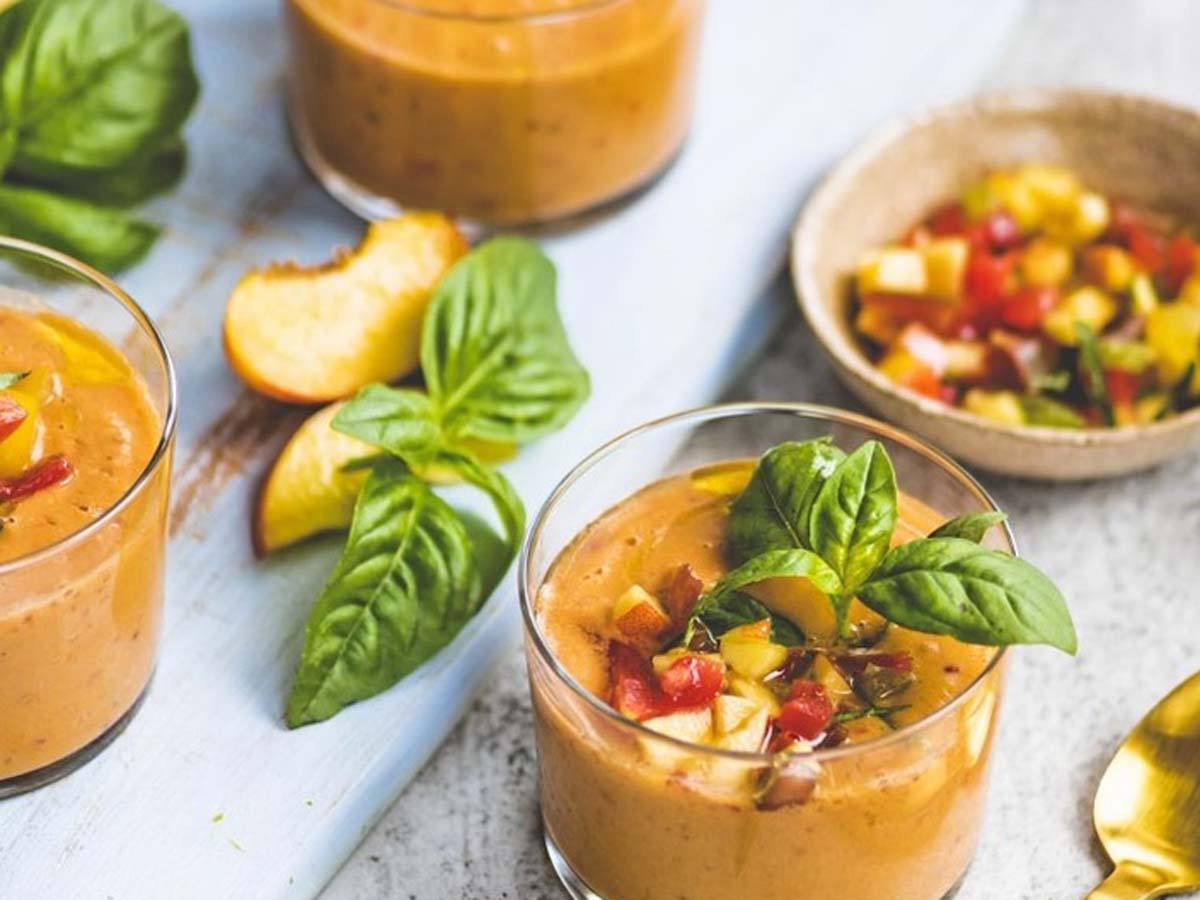 A classic bright red cold Spanish gazpacho soup garnished with fresh herbs.