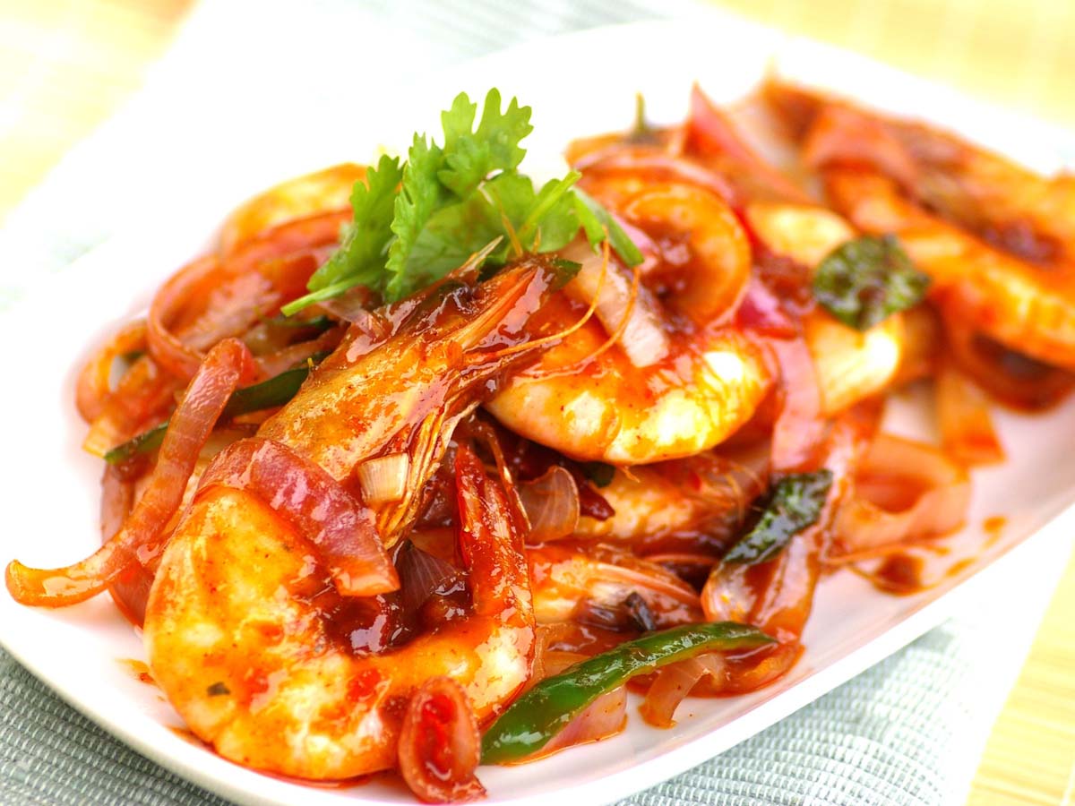 A plate of sizzling pan-seared spicy prawns seasoned with chili and garlic butter sauce.