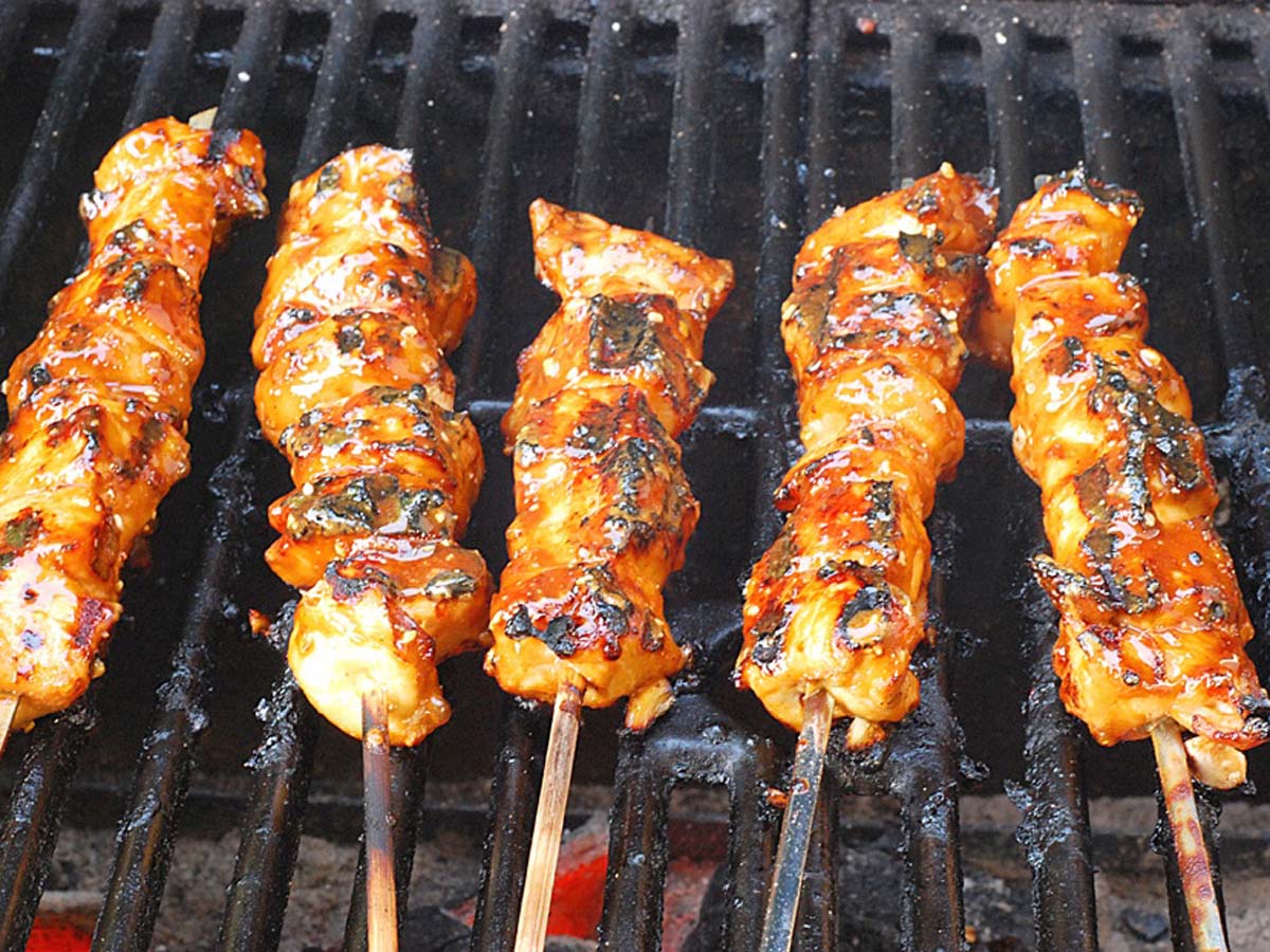 Grilled tandoori chicken kebabs with charred peppers and onions on wooden skewers.