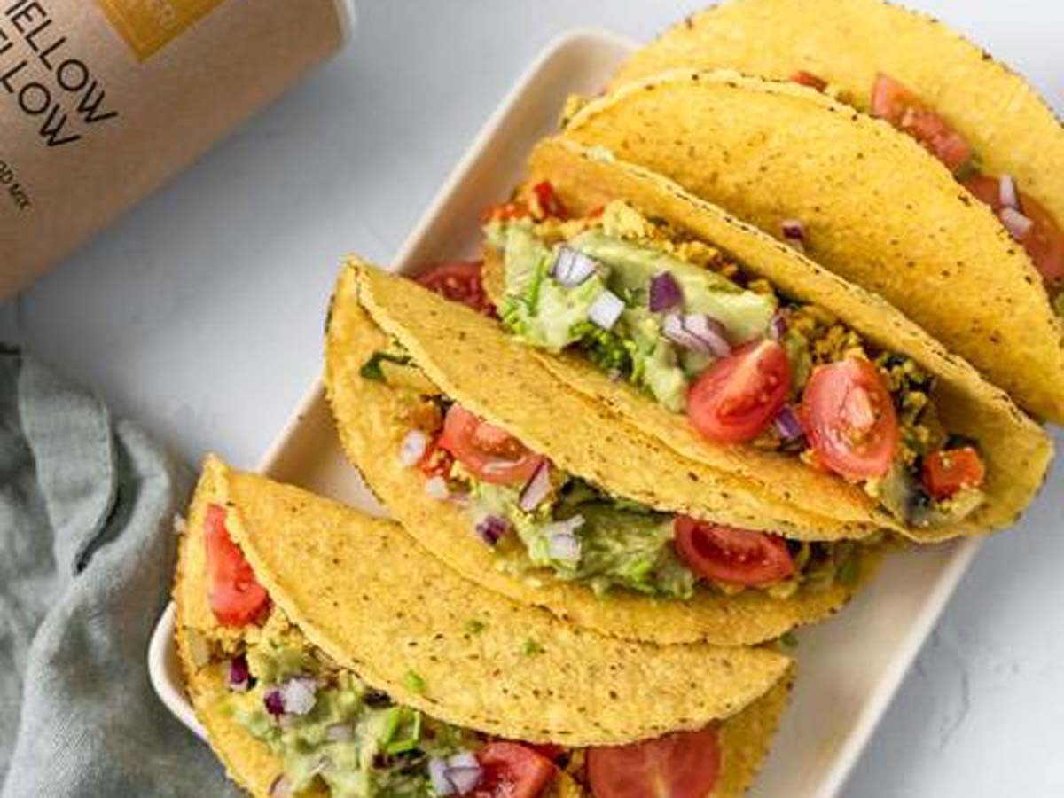Two vibrant vegan breakfast tacos stuffed with avocado, black beans, and salsa mix.