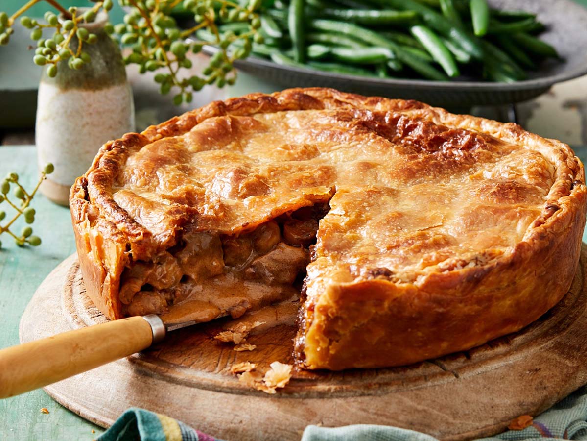 A hearty, golden brown baked venison pie with a flaky puff pastry lid shell.